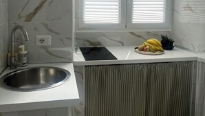 Une cuisine moderne dotée d’un évier encastré, d’une plaque de cuisson et d’une fenêtre avec des stores.