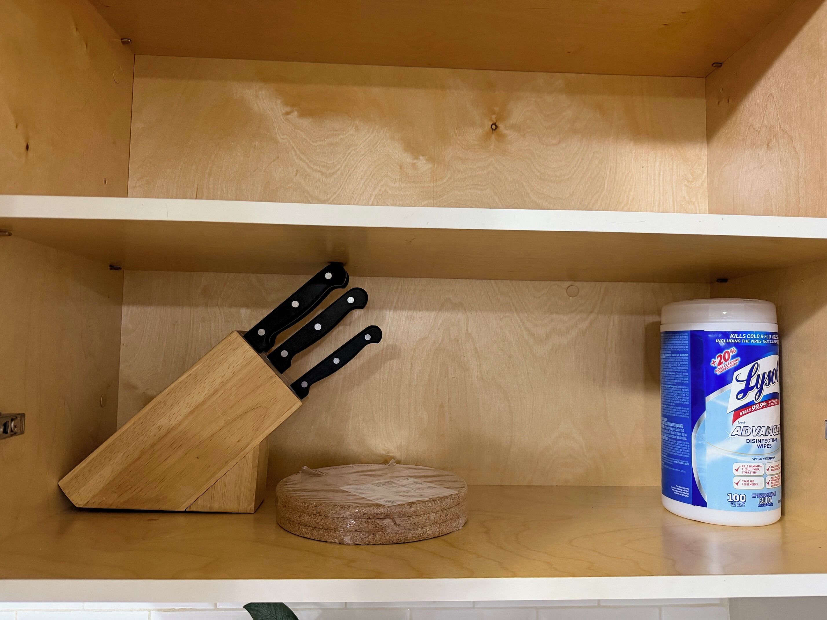 Un armario de cocina de madera con un organizador de cuchillos y un envase de toallitas desinfectantes Lysol.
