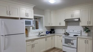 A kitchen with white cabinets, a refrigerator, a microwave, a sink, a stove, and a dishwasher.