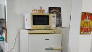 A small, white refrigerator with a microwave on top, a door handle, and a brand name 'Consul'.