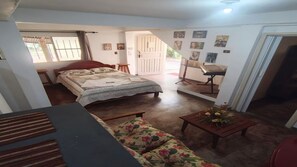 A bedroom with a bed, a floral sofa, a small table with flowers, a desk with a chair, and a door leading to another room. - House in the city center/3 beds/Garage/Netflix and Amazon Prime. (Rio das Flores)