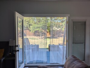 Une pièce dotée d’une porte-fenêtre coulissante donnant sur un jardin avec une pelouse et une clôture en bois.