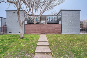 Un edificio moderno con fachada de ladrillo, una puerta de garaje grande y un árbol en primer plano.