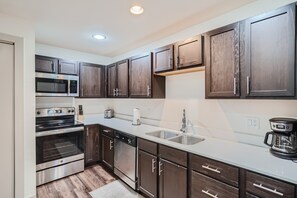 Una cocina moderna con armarios de madera oscura, electrodomésticos de acero inoxidable y encimera blanca.