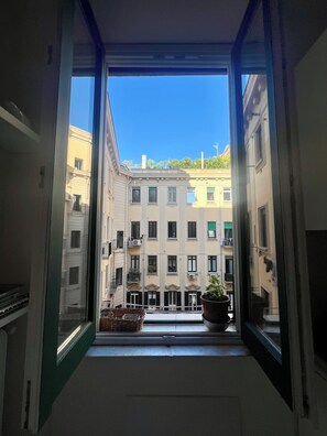 A view from a balcony with a clear blue sky, a potted plant, and a building with multiple windows and balconies. - A bright and centrally located, newly renovated studio apartment in an elegant building (Napoli)