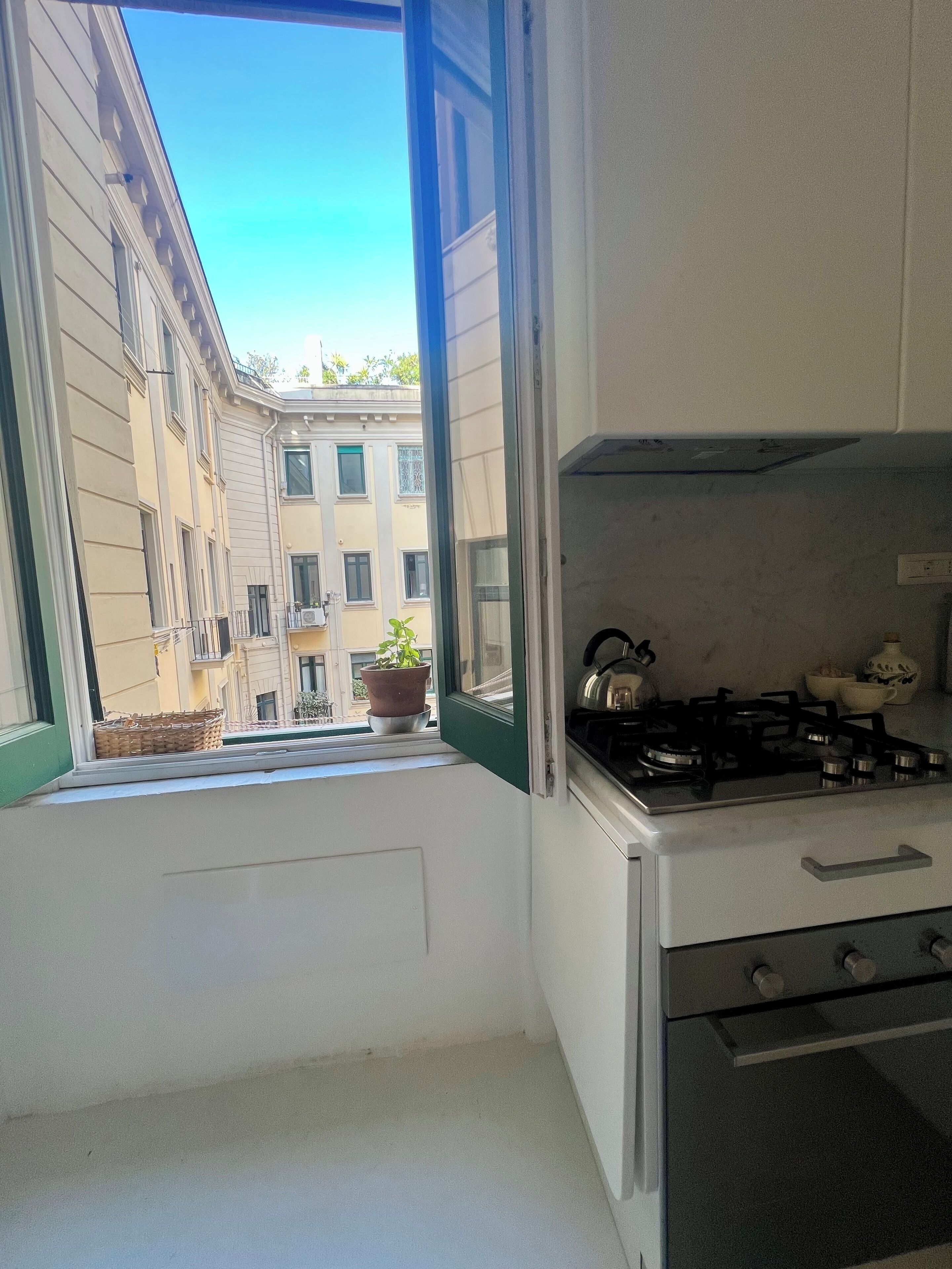 A kitchen with a window, a stove, and a view of a building.