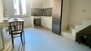 A modern kitchen with white cabinetry, a built-in oven, and a stainless steel refrigerator.