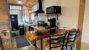 A kitchen with a wooden countertop, a microwave, a stove, and a sink.