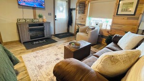 A cabin interior with a television, a cabinet, a sofa, and a chair.