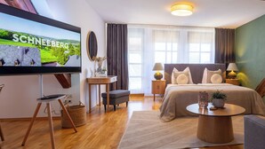 Ett modernt hotellrum med en stor säng, en soffa, en fåtölj, en TV och ett litet bord.