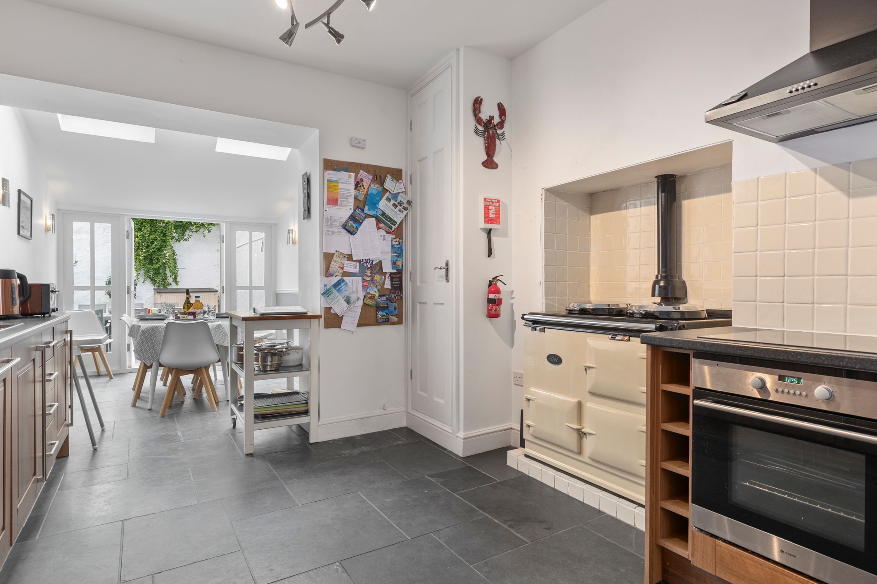 A modern kitchen with a built-in oven, a stove, and a dining area with a table and chairs.
