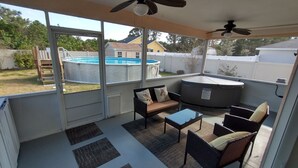 A covered patio area with a pool, outdoor furniture, and ceiling fans.