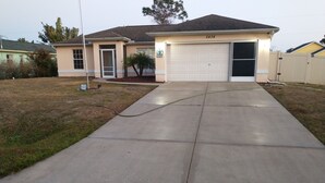 A single-story house with a garage, a driveway, and a small lawn.