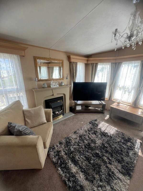 A living room with a sofa, a flat-screen TV, a fireplace, and a chandelier. - The Chase - Holiday Accommodation 21863 (Skegness)