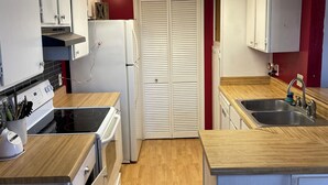 A compact kitchen with a stove, sink, and white cabinets.