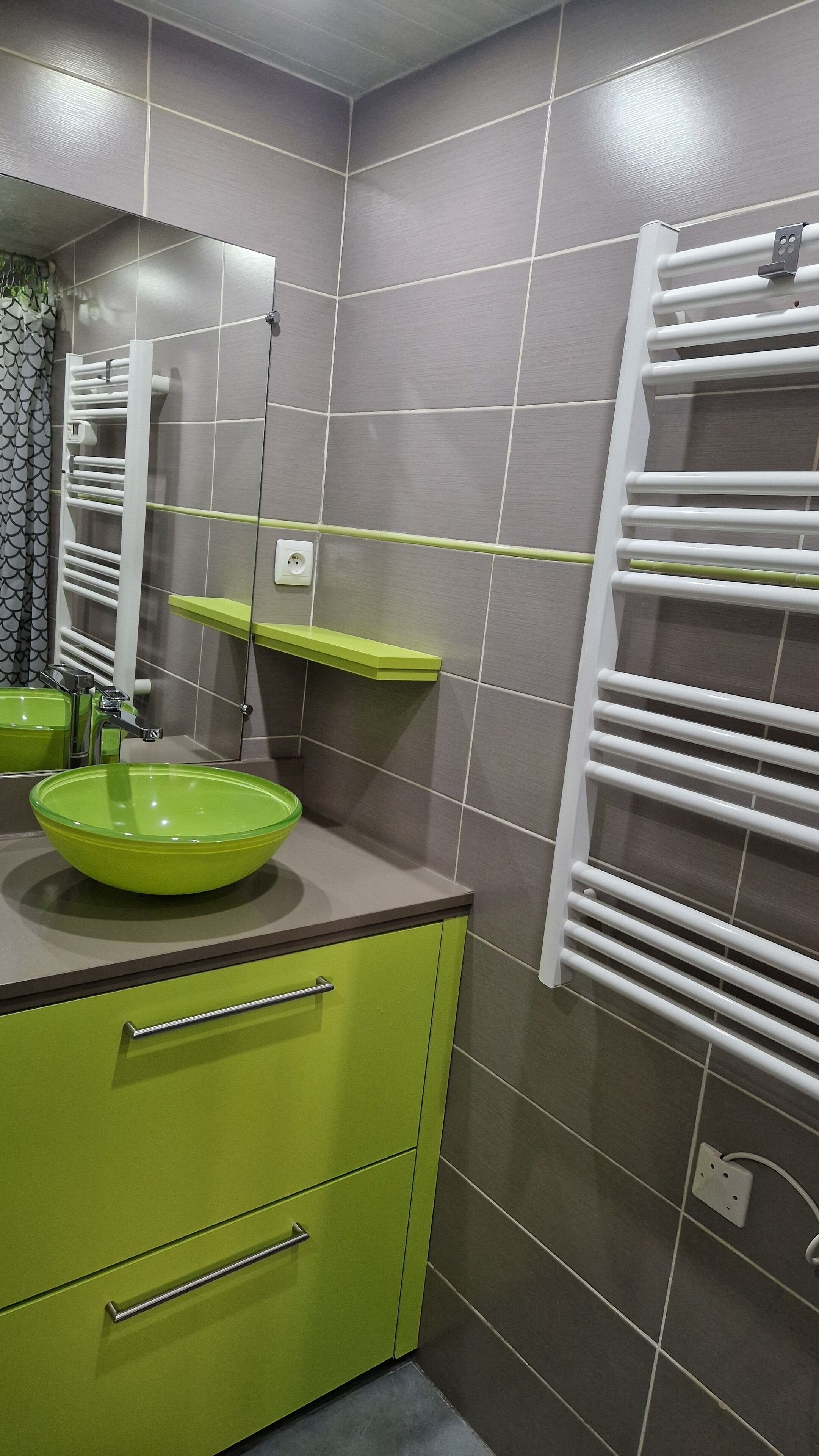 Ein modernes Badezimmer mit einem grünen Waschbecken, einem Spiegel und einem weißen Handtuchhalter.