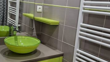 Ein modernes Badezimmer mit einem grünen Waschbecken, einem Spiegel und einem weißen Handtuchhalter.
