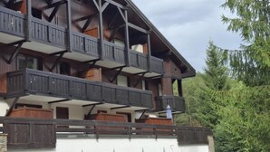 A multi-story building with balconies, wooden railings, and a white facade.