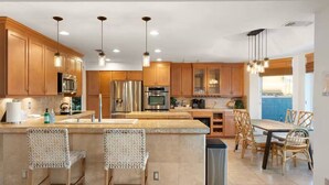 Une cuisine moderne avec des meubles en bois, des appareils en acier inoxydable et un îlot central doté de tabourets de bar.
