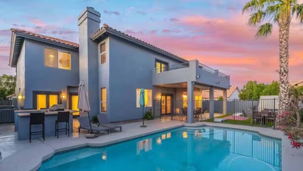 Une maison moderne à deux étages dotée d’une piscine, d’un bar extérieur et d’un espace détente sur la terrasse.