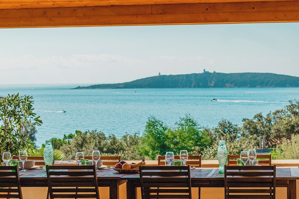 Espace repas sous la grande terrasse couverte avec une splendide vue mer à 180°