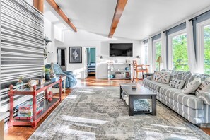 En moderne stue med en stribet sofa, et sofabord og et fjernsyn ophængt på væggen.