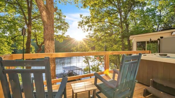 Eine Holzterrasse mit Stühlen und einem Whirlpool mit Blick auf ein Gewässer.