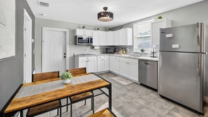 A modern kitchen with white cabinets, stainless steel appliances, and a wooden dining table. - Modern Guesthouse with W/D, 6 mins to DT St Pete (St. Petersburg)