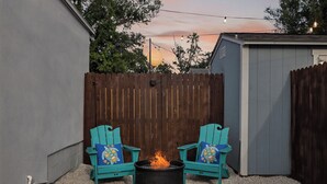 A backyard with a fire pit and two turquoise Adirondack chairs with decorative pillows. - Modern Guesthouse with W/D, 6 mins to DT St Pete (St. Petersburg)