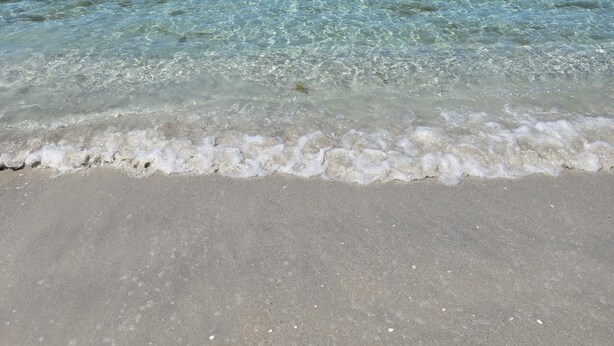 Ein Strand mit klarem Wasser und sandigem Ufer.