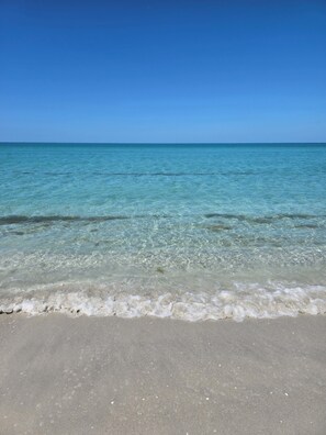 Ein Strand mit klarem Wasser und sandigem Ufer.