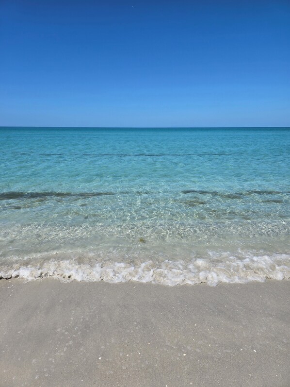 A beach with clear water and a sandy shore.