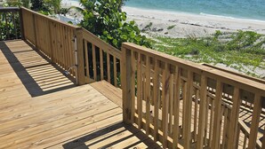 Eine Holzterrasse mit Blick auf Strand und Meer.