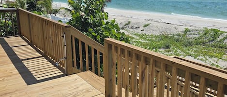 A wooden deck with a view of a beach and ocean.