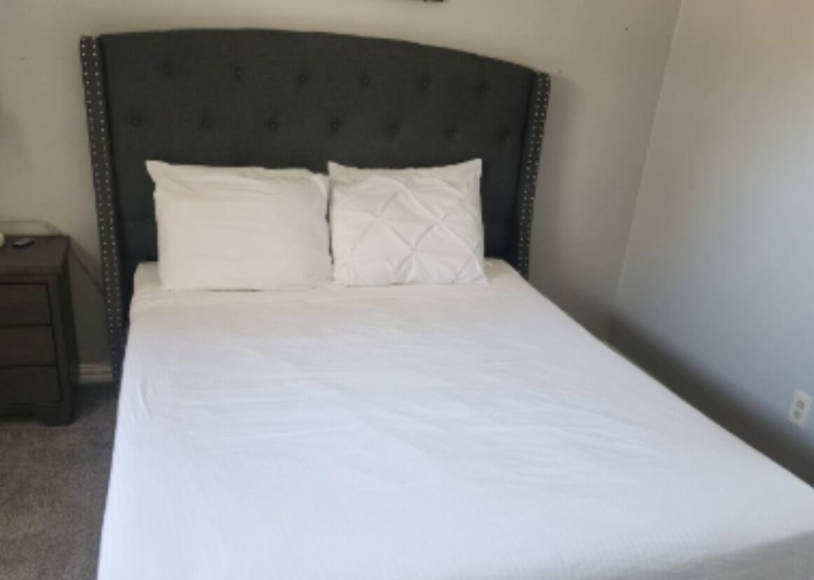 Una cama bien hecha con un cabecero oscuro y dos almohadas.
