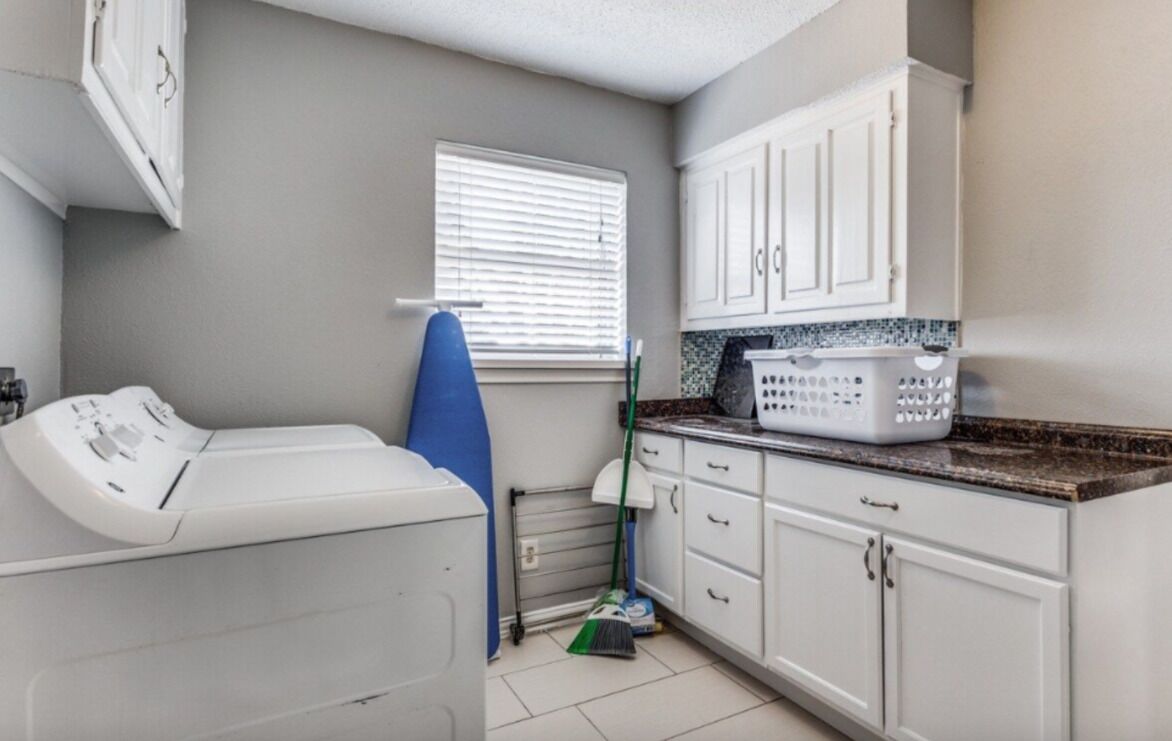 A laundry room with a washing machine, a drying rack, and a mop.