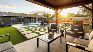 Un patio trasero con piscina, mobiliario exterior y zona de barbacoa.