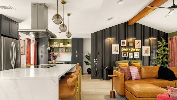 Una cocina moderna con una isla de mármol, un área de comedor con un sofá y una sala de estar con un amplio sofá modular.