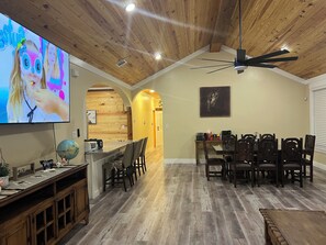 A dining area with a wooden ceiling and a TV displaying animated characters. - Home in Fort Worth (Fort Worth)