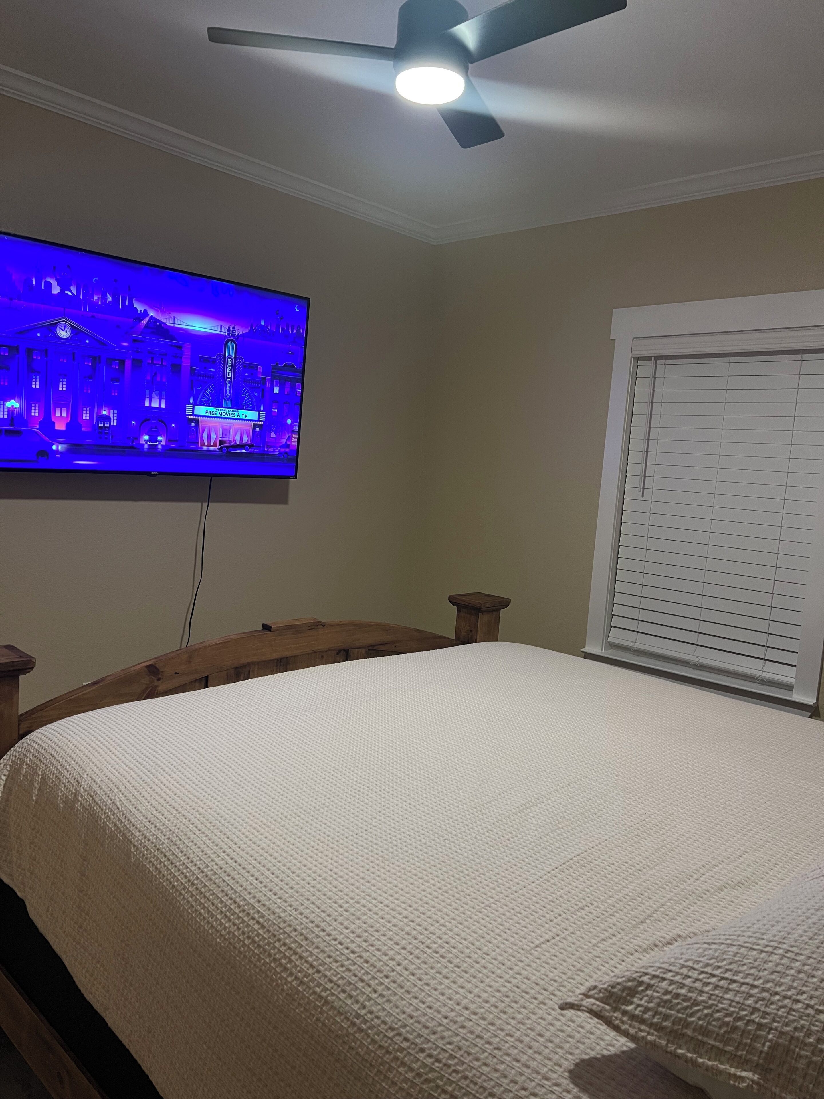 Una camera da letto con un letto, una ventola a soffitto e una televisione che mostra una vista sulla città.