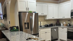 A modern kitchen with white cabinets, stainless steel appliances, and a granite countertop. - Home in Fort Worth (Fort Worth)