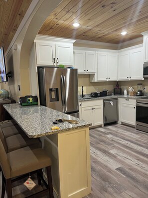 A modern kitchen with white cabinets, stainless steel appliances, and a granite countertop. - Home in Fort Worth (Fort Worth)