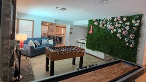 A room with a foosball table, a sofa, and a green wall with flowers. - Winding Hollow : Spacious 5-bedroom house in tranquil Arlington (Arlington)