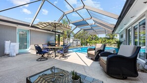 Eine überdachte Terrasse im Freien mit Pool, Sitzbereich und Grill.
