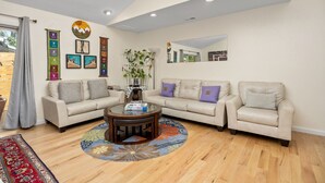 A living room with two beige sofas, a coffee table, and a decorative wall with framed artwork and a plant. - 2-beds, 3 baths, 1 office, full kitchen townhome in beautiful Boulder, heat & AC (Boulder)