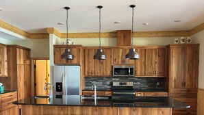 Une cuisine moderne avec des meubles en bois, des appareils électroménagers en acier inoxydable et un îlot central doté de tabourets de bar.