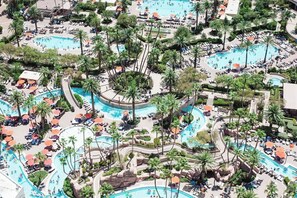 Un resort con diverse piscine, palme e lettini prendisole.