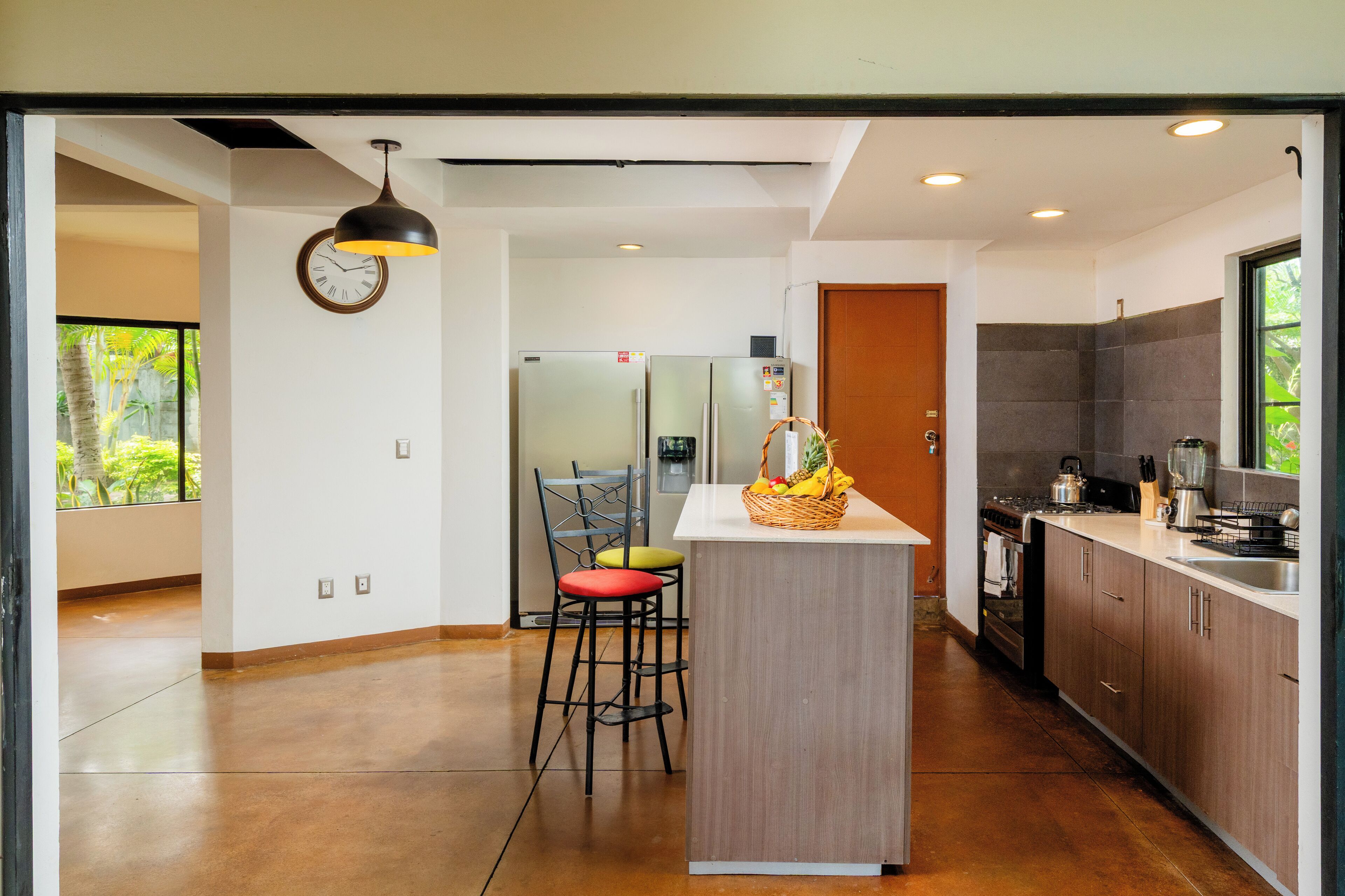 A modern kitchen with a central island, stainless steel appliances, and a view of the outdoors.