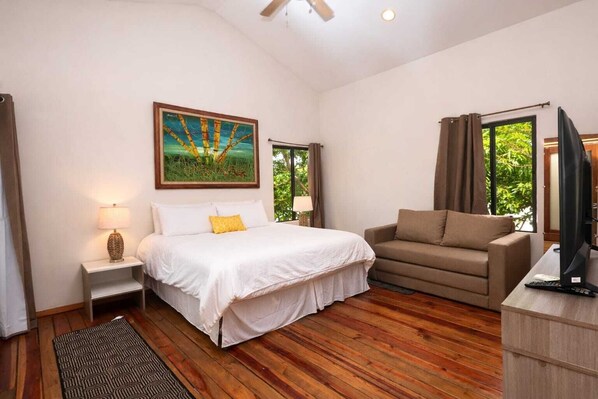 A bedroom with a bed, a sofa, a TV, and a painting on the wall. - Casa Milo (Managua)