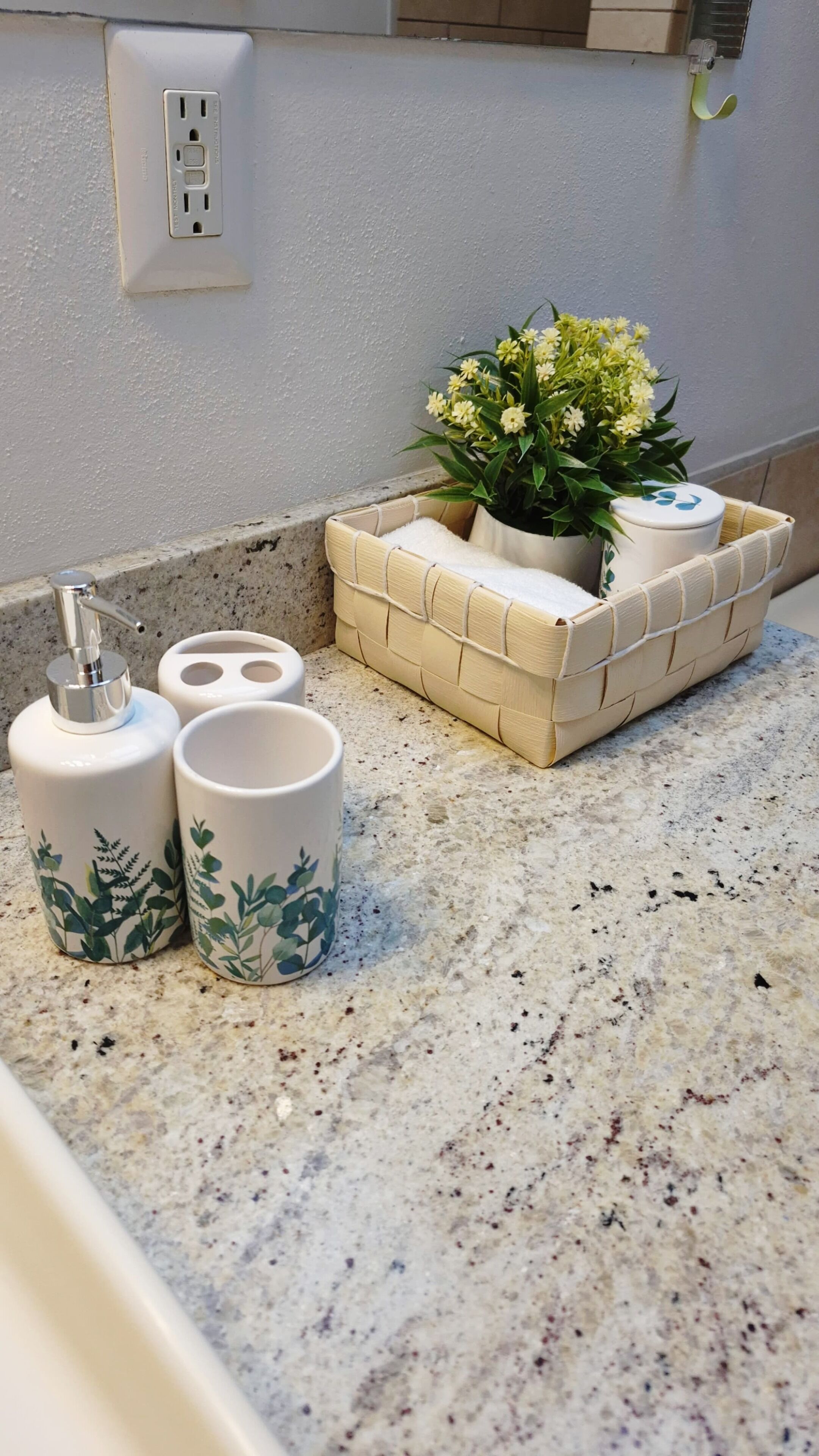 A bathroom countertop with a soap dispenser, two cups, a small plant, and a soap dish.